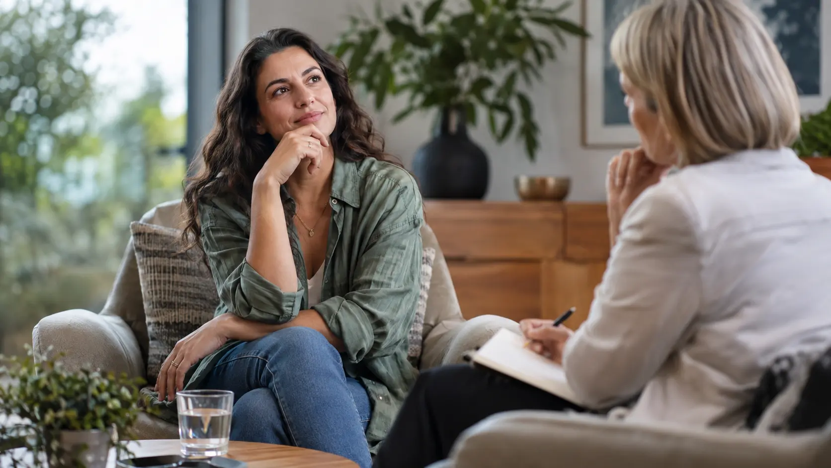 Woman pausing thoughtfully while another woman holds a notebook